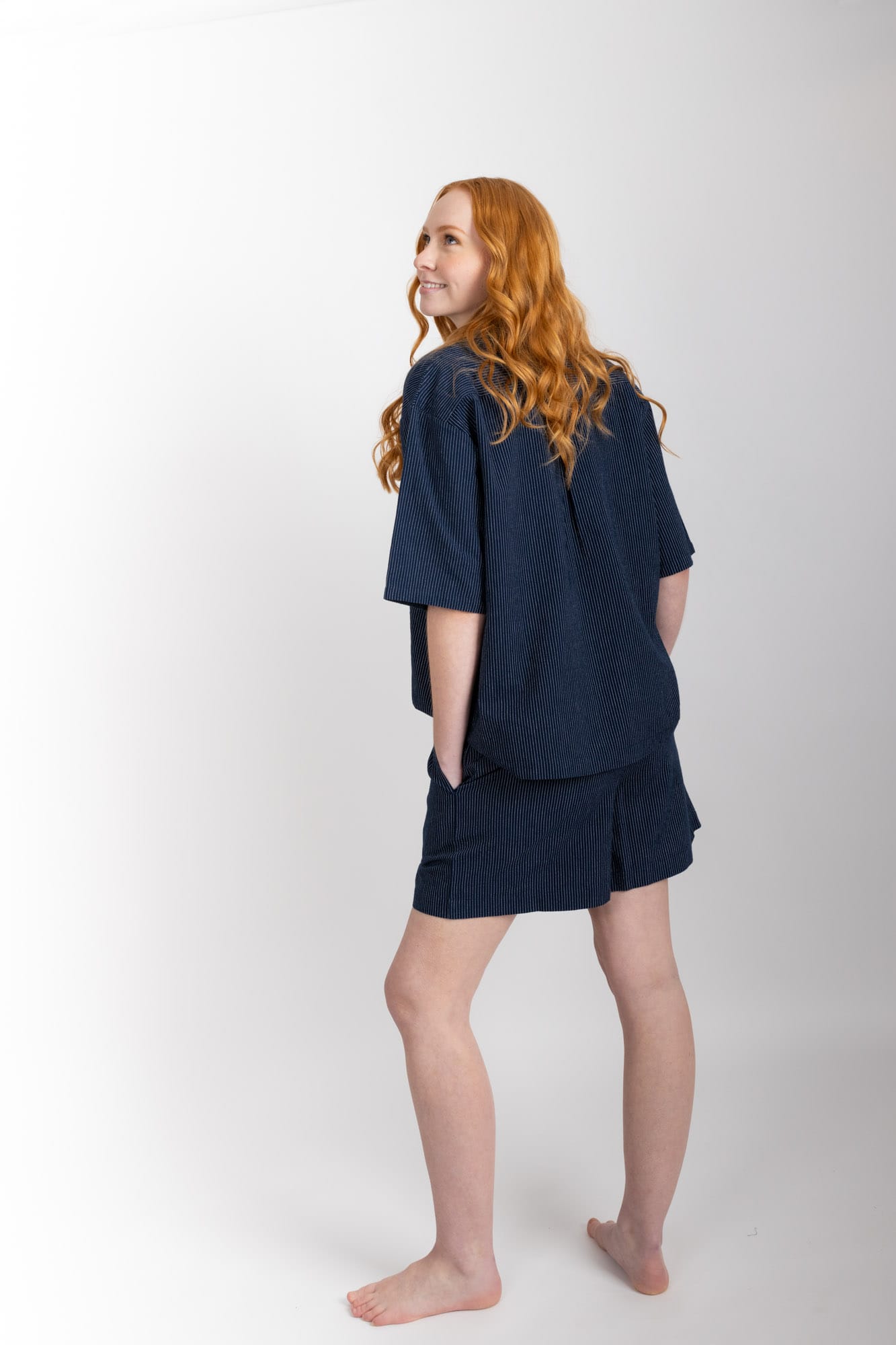 Women’s pyjama set including a short sleeve shirt and shorts. Made from organic cotton, in Navy pinstripe.  The shirt has shell buttons, a front pocket and a back pleat with locker loop detail.  The shorts feature natural shell buttons and an elasticated waistband for comfort.