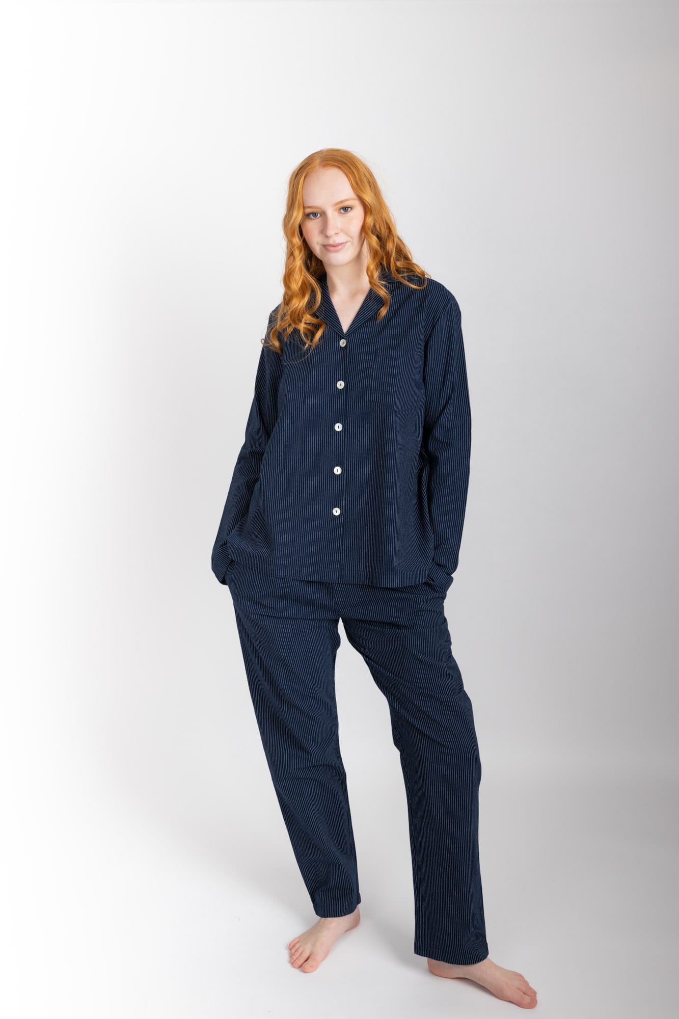 Women’s pyjama set including a long sleeve shirt and long sleeve pants. Made from organic cotton, in a Navy pinstripe.  The shirt has shell buttons, a front pocket and a back pleat.  The pants feature an elasticated waistband for comfort.