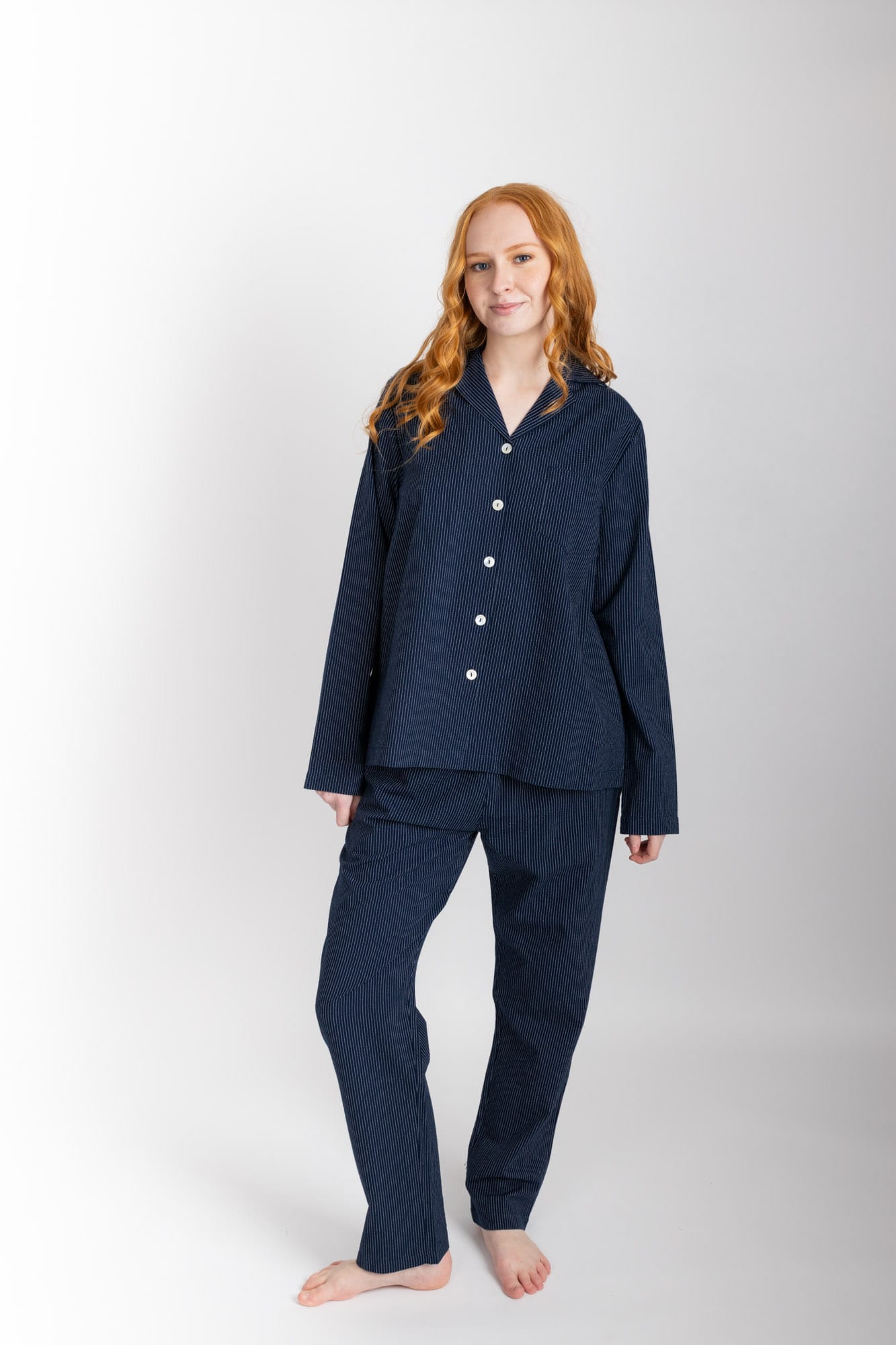 Women’s pyjama set including a long sleeve shirt and long sleeve pants. Made from organic cotton, in a Navy pinstripe.  The shirt has shell buttons, a front pocket and a back pleat.  The pants feature an elasticated waistband for comfort.
