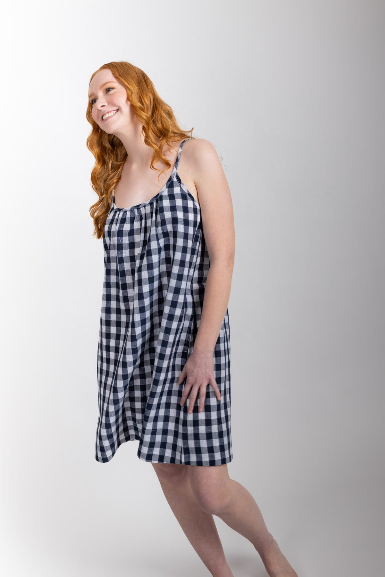 This knee length women’s nightdress dress features a scoop neck, adjustable spaghetti straps and side pockets. Finished with a wide hem, French seams, it is made from an organic cotton and linen blend, in a pink and white check