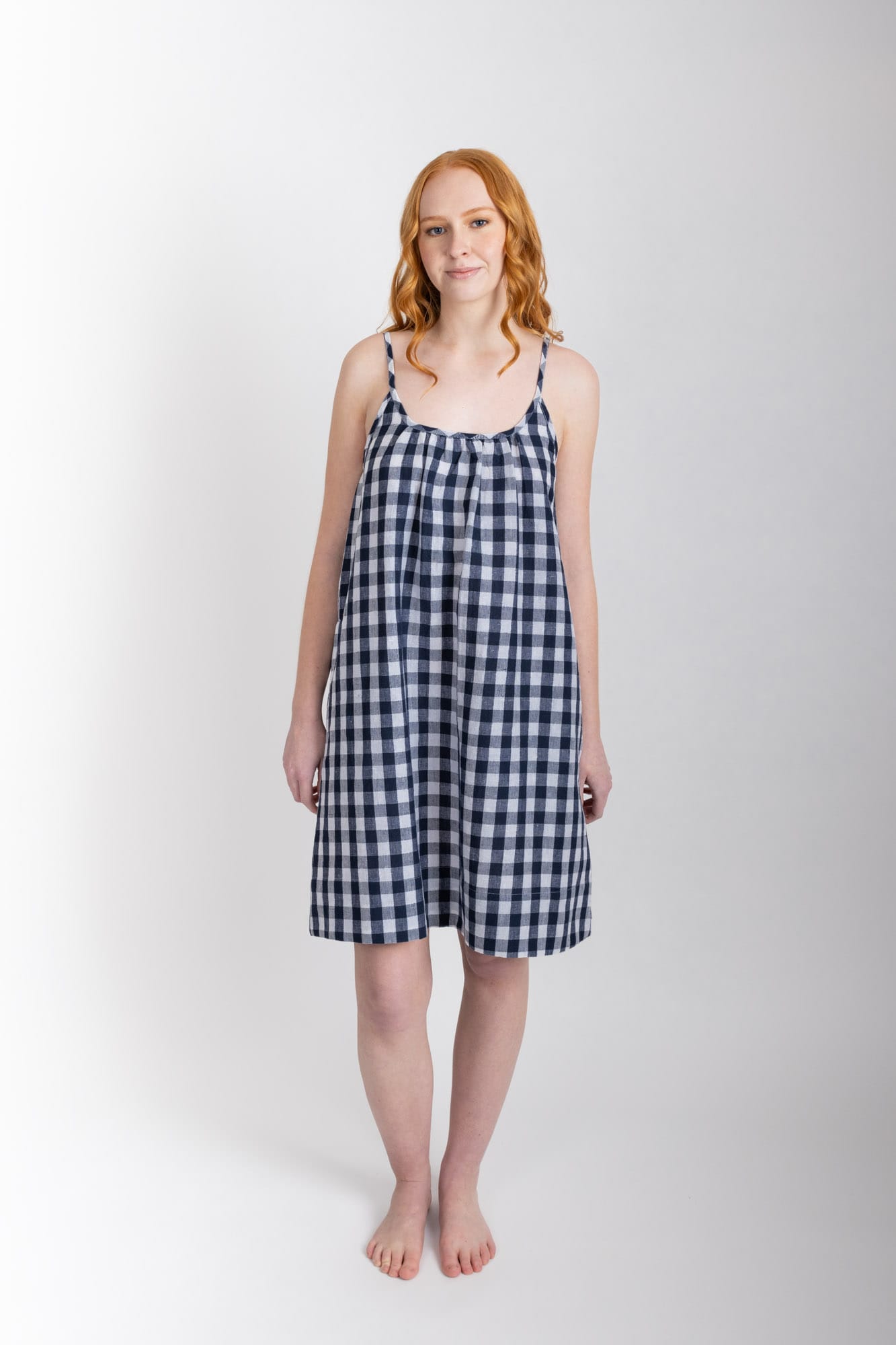 This knee length women’s nightdress dress features a scoop neck, adjustable spaghetti straps and side pockets. Finished with a wide hem, French seams, it is made from an organic cotton and linen blend, in a navy check