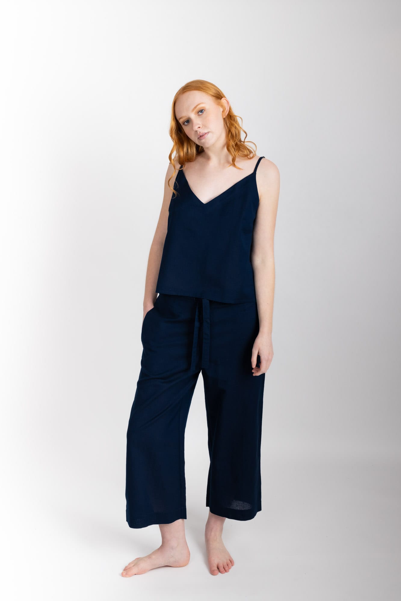 Women’s sleepwear set featuring a V-neck, swing-style camisole with adjustable straps. Paired with straight-leg cropped pant with an elasticated waist, flat front, and drawstring detail, these pants are comfortable and flattering. Woven in 100% organic cotton, both pieces have been finished with French seams.