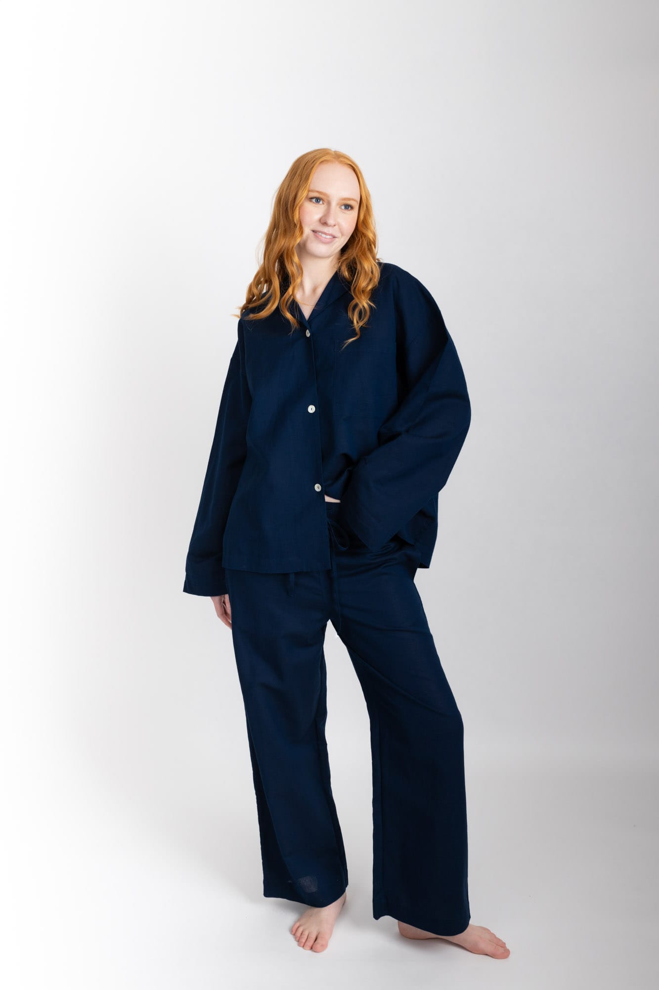 Women’s sleepwear set featuring an oversized, dropped-shoulder, button-through shirt, with natural shell buttons.  The loose-fit, straight-leg pants have an elasticated waist, flat front, and drawstring detail, and are comfortable and flattering. Made from an organic cotton and linen blend in Navy, both pieces have been finished with French seams.