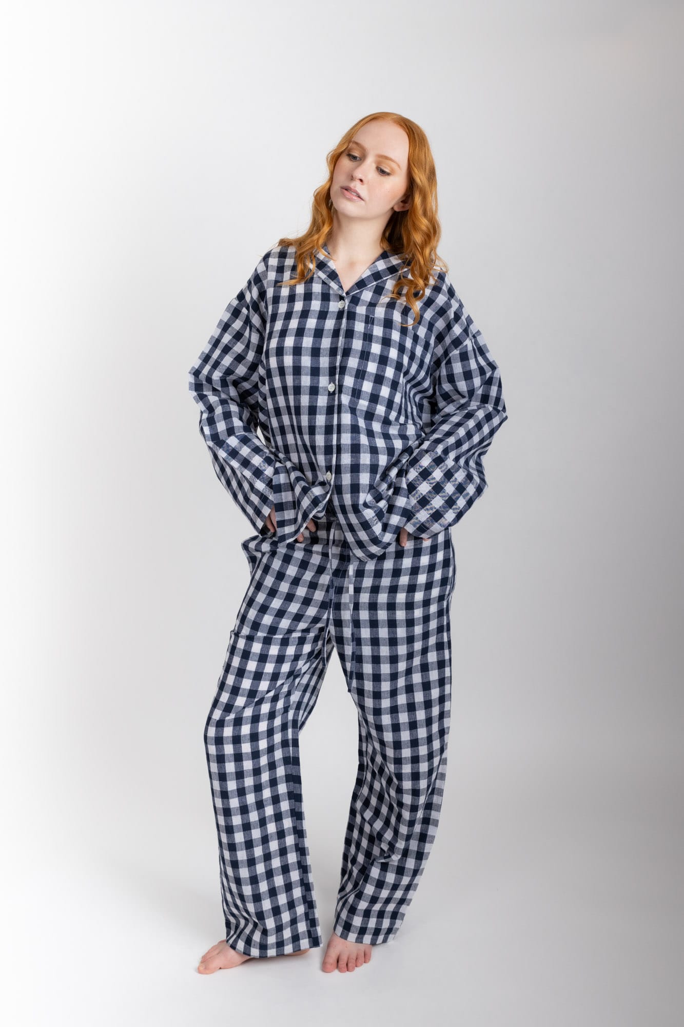 Women’s sleepwear set featuring an oversized, dropped-shoulder, button-through shirt, with natural shell buttons.  The loose-fit, straight-leg pants have an elasticated waist, flat front, and drawstring detail, and are comfortable and flattering. Made from an organic cotton and linen blend, in a navy and white check, both pieces have been finished with French seams.